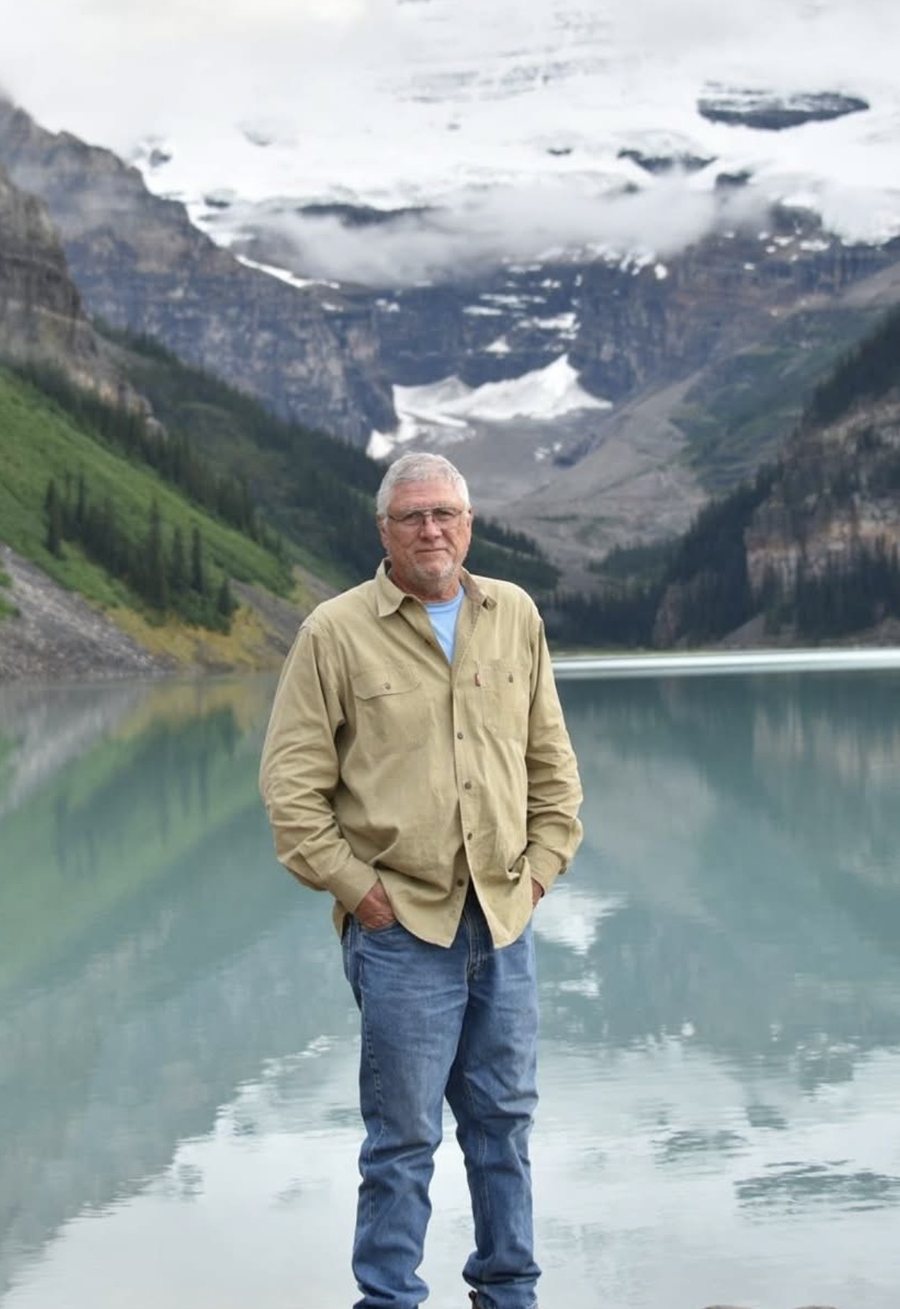 Mark Mattox, founder of EMC, standing at the edge of a mountain lake